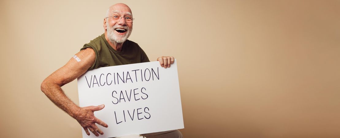 Cheerful man holding a banner with "vaccination saves lives" slogan