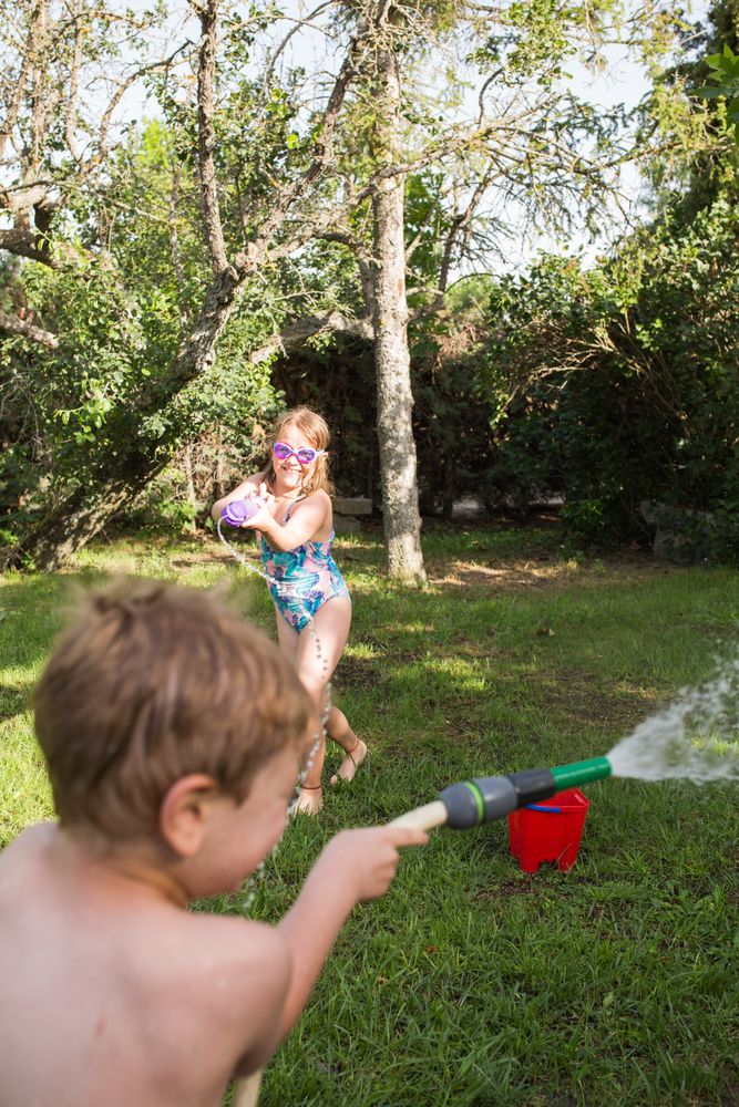 Little kids in swimwear having fun with splashing water