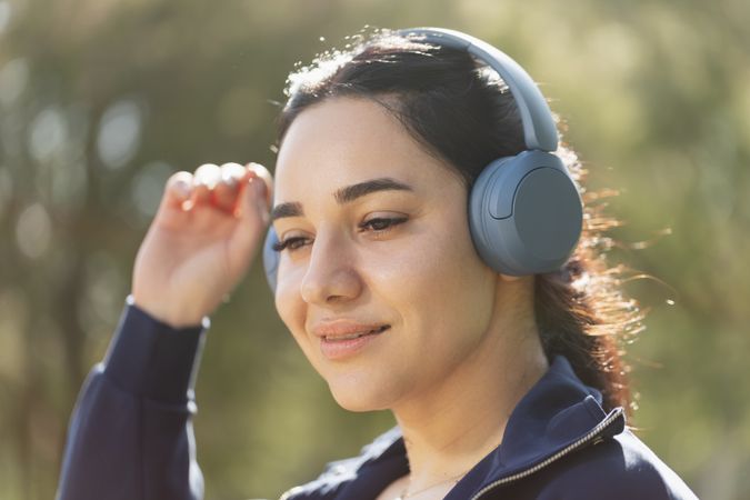 A woman relaxes and enjoys the music she listens to with her headphones, while walking and exercising in the park