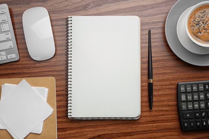 Notebook with cup of coffee and office tools on wooden background