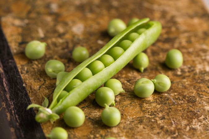 Fresh peas and pea pods on dark background