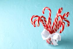 Candy canes in glass jar on blue background, space for text