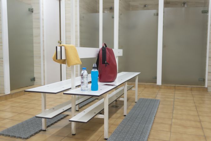 Empty changing rooms with backpack and drinks on bench
