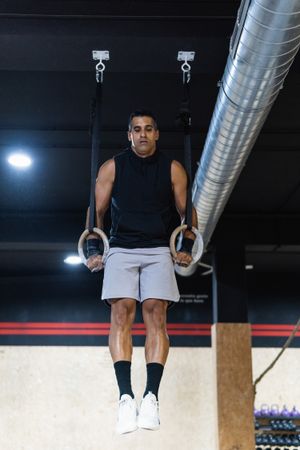 Hispanic sportsman exercising with gymnastic rings