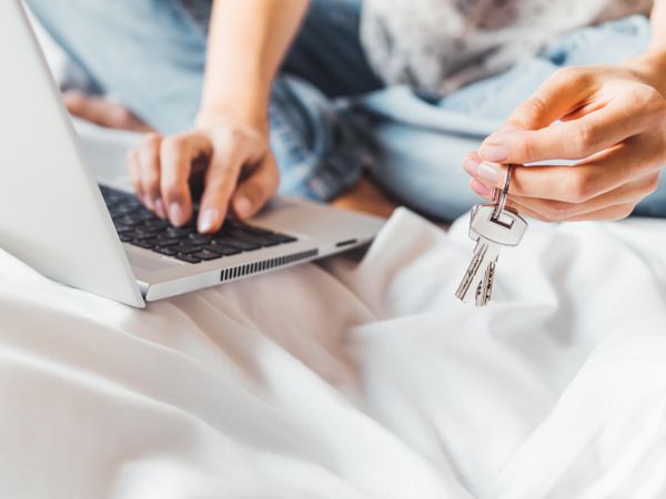 Woman uses laptop in bed to pay bills or book a hotel room