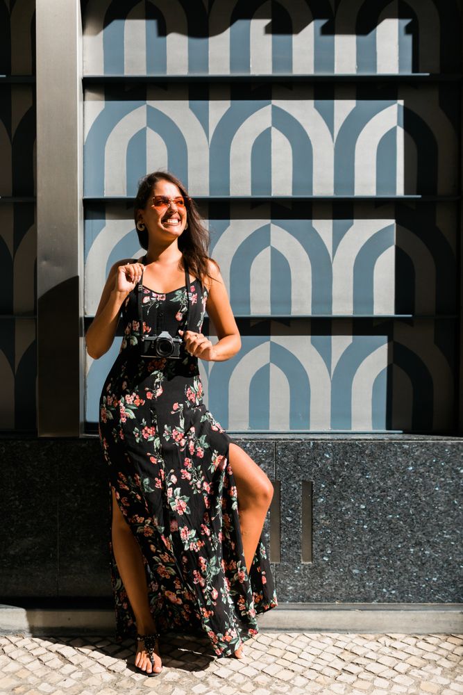 Dreamy stylish woman in sunglasses standing on city street