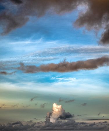 Light and grey clouds in blue sky, vertical