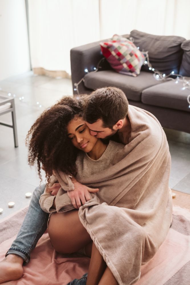 Multiethnic couple hugging on floor at home