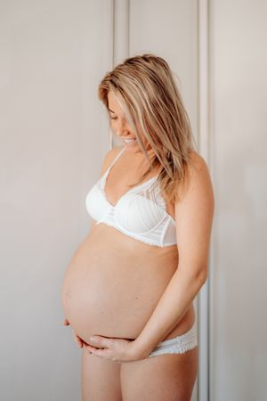 Smiling pregnant woman touching naked abdomen