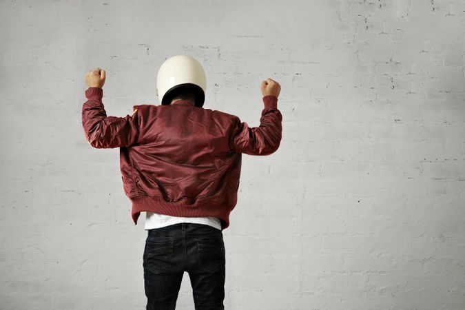 Rearshot of man with arms in the air wearing dark red leather jacket and helmet