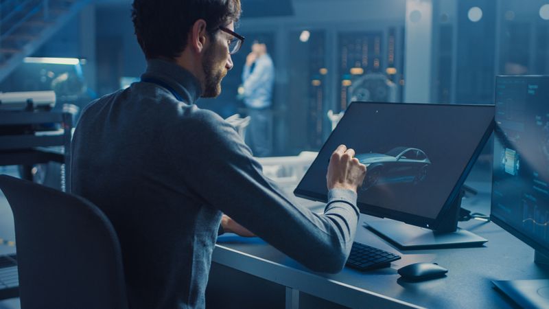 Professional Automotive Graphic Designer is Working on Concept Car Render with a Stylus Pen in a High Tech Innovative Laboratory with a Prototype Car Chassis.