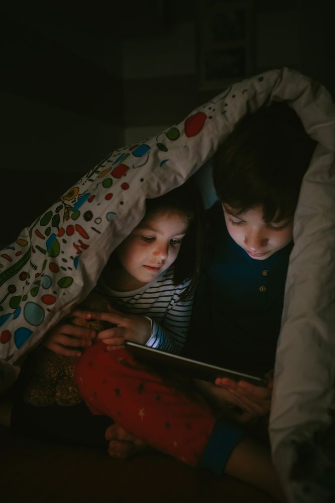 Siblings looking at the tablet in the dark