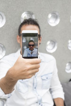 Phone screen of male in sunglasses taking picture
