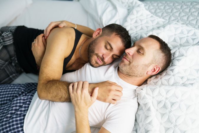 Male lying on his partners chest in bed