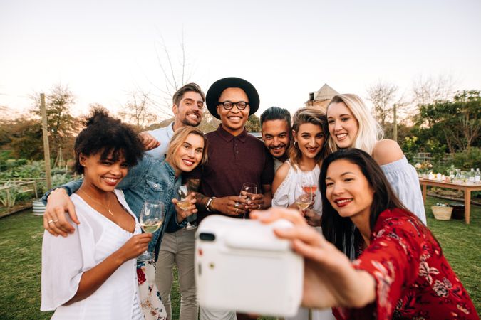 Woman with friends taking selfie using instant camera