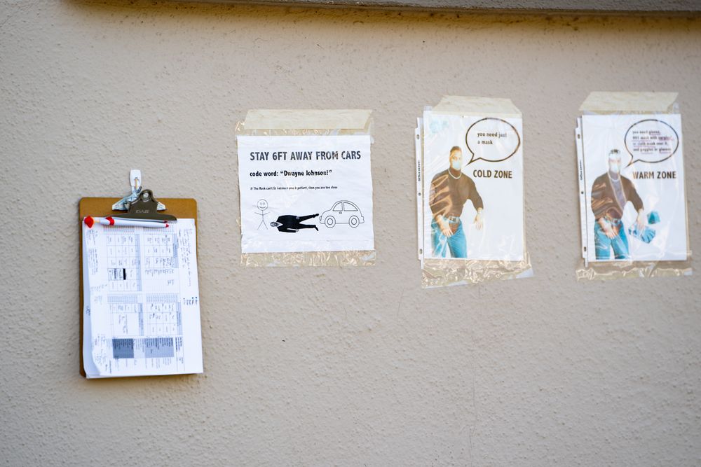 Signs taped to wall at public COVID-19 testing site for cold zone and warm zone