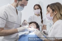 A portrait of dental team team working on young male patient bEL7o4