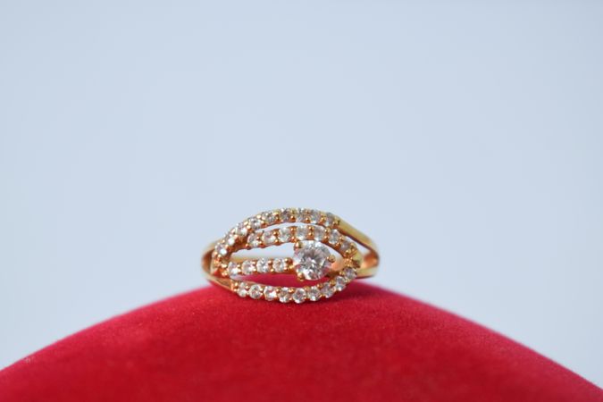 Woman's diamond ring resting on red pillow
