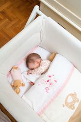Newborn baby girl sleeping in a cot with pacifier and toy