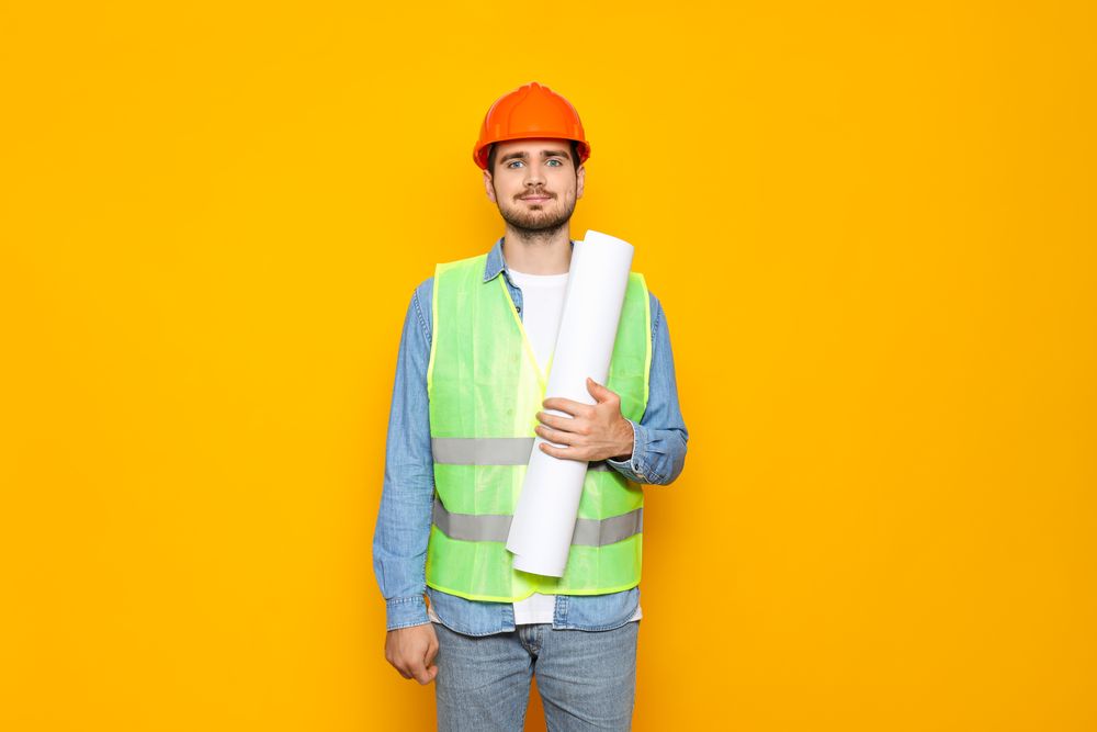 Young man civil engineer on yellow background