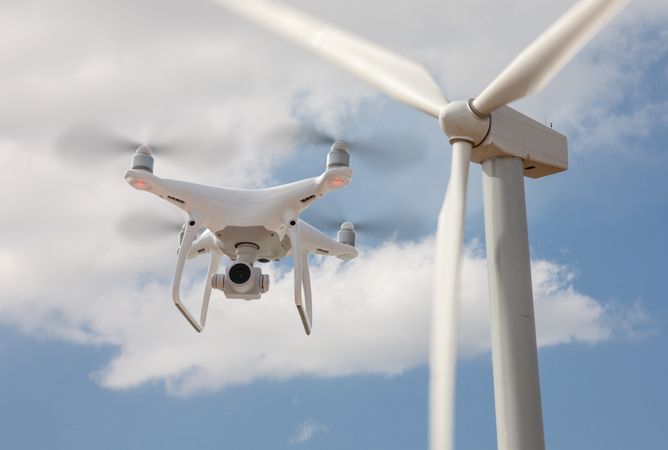 Unmanned Aircraft System (UAV) Quadcopter Drone In The Air Surveying Wind Turbines.