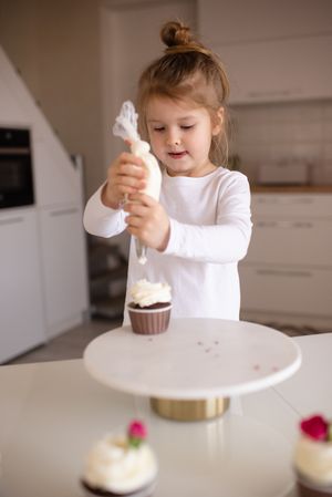 Girl decorating cupcake with whipped cream