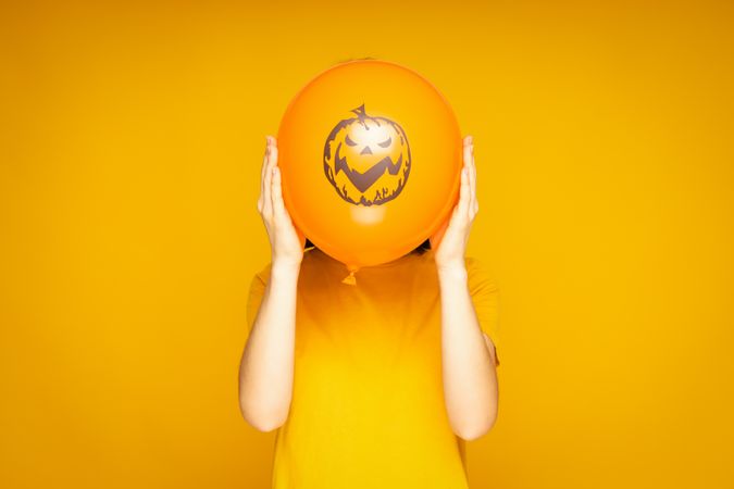 Concept of Halloween, Woman holds Halloween balloon on yellow background