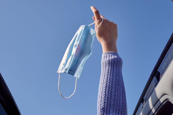 Crop faceless woman outstretching hand with face mask