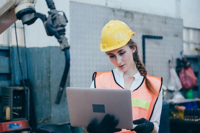 Female worker in manufacturing factory in high-vis jacket and hard hat