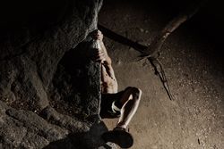 Man practicing rock climbing among large rocks in a forest