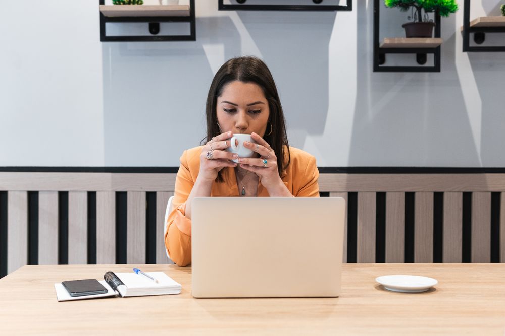 Woman working in cafe and drinking coffee