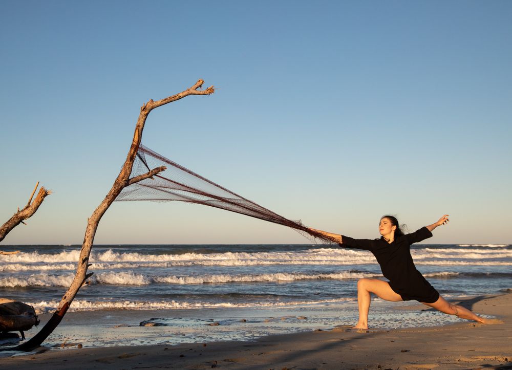Woman in fishing net fixed on twig near water on shore