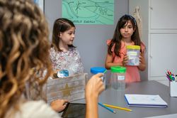 Student looking at teacher while holding sorting waste bin