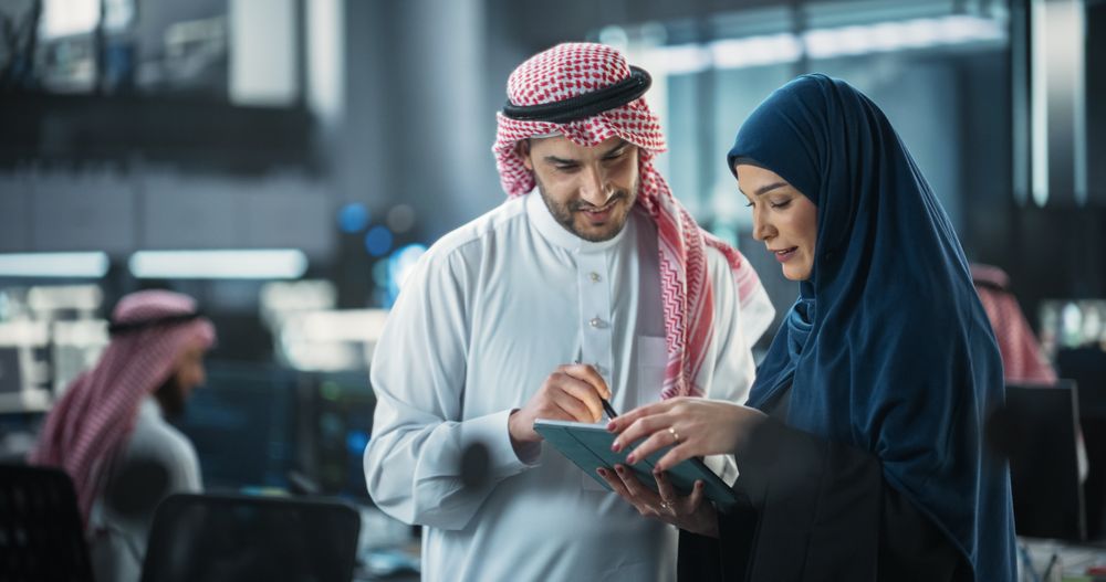 Team of Two Diverse Specialists Use Tablet Computer. Having a Conversation on a Cybersecurity Project.