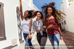Young woman jumping in joy while walking with friends on a street 0WeNO4