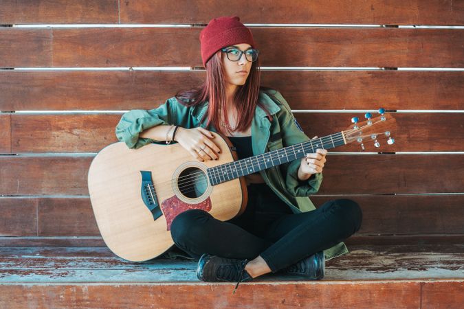 Romantic woman playing guitar leaning on wall