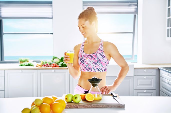 Healthy woman drinking fresh juice in a bright kitchen