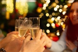 Friends toasting with champagne glasses against a background of festive bokeh lights.