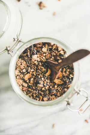 Top view glass container of homemade granola, close up, with copy space