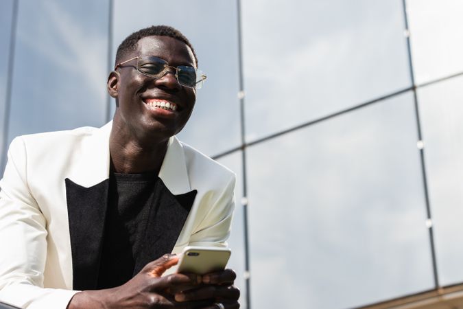Content Black businessman with smartphone on city street
