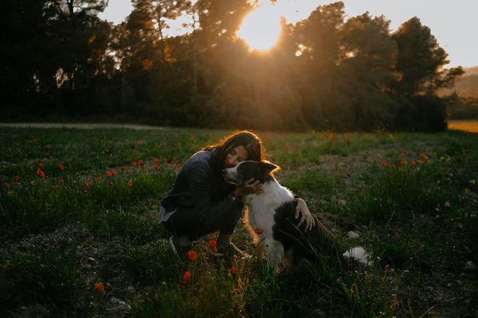 Woman kissing dog on meadow