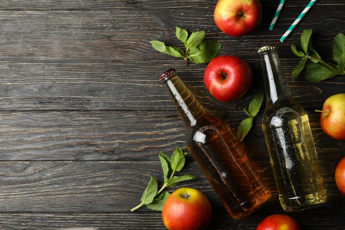 Composition with cider, apples and straws on wooden background