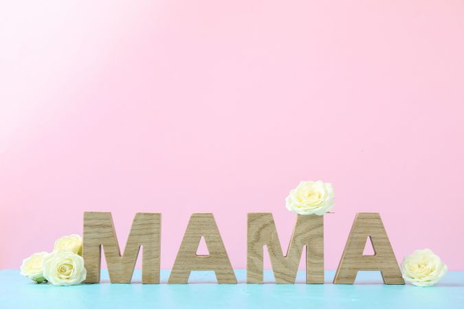 Inscription Mom with roses on blue table against color background, space for text