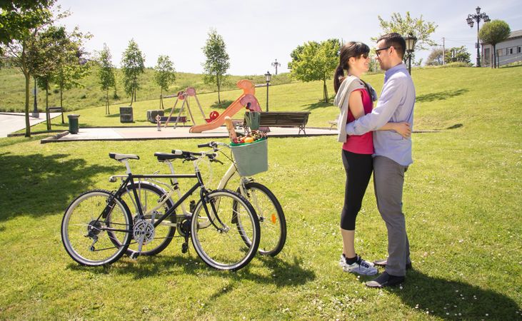 Couple in love embraced beside of bicycles on park