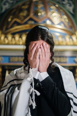 Jewish man wearing suit and Kittel praying in synagogue