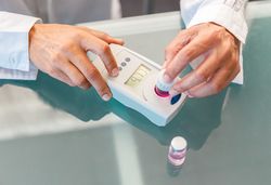 Assistant working in lab with pink liquid