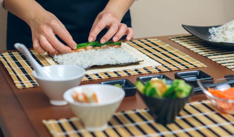 Chef placing ingredients atop rice while making fresh sushi