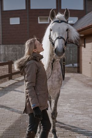 Warm dressed woman with gray horse outside