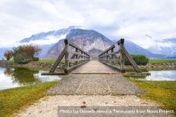 Wooden bridge leading to ale with mountains behind 5XMLo4
