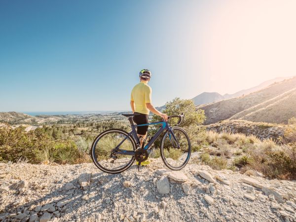 man resting and enjoying the views while riding a bicycle on a mountain road